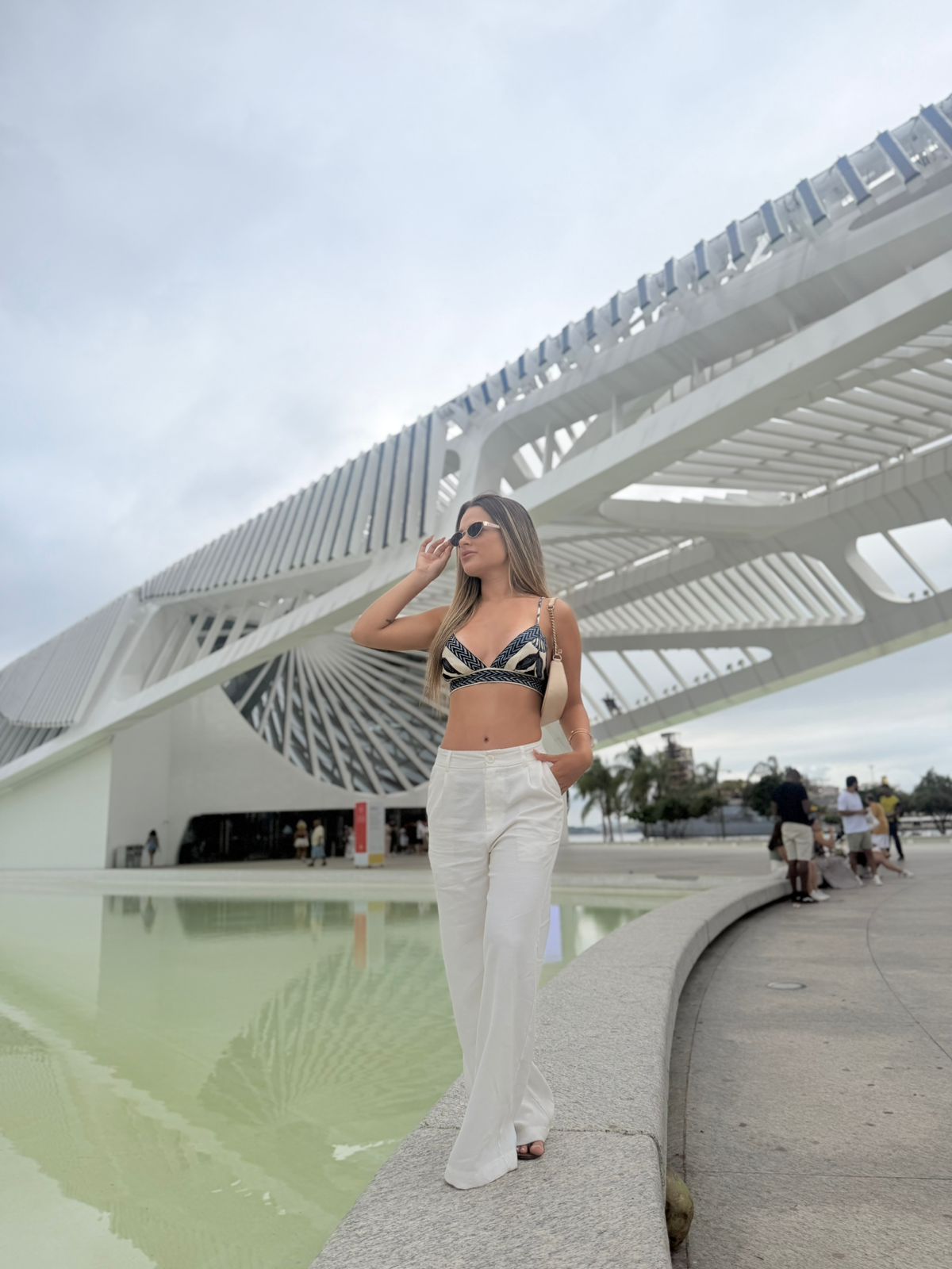 Bruna usando um look branco em um cenário arquitetônico ao ar livre